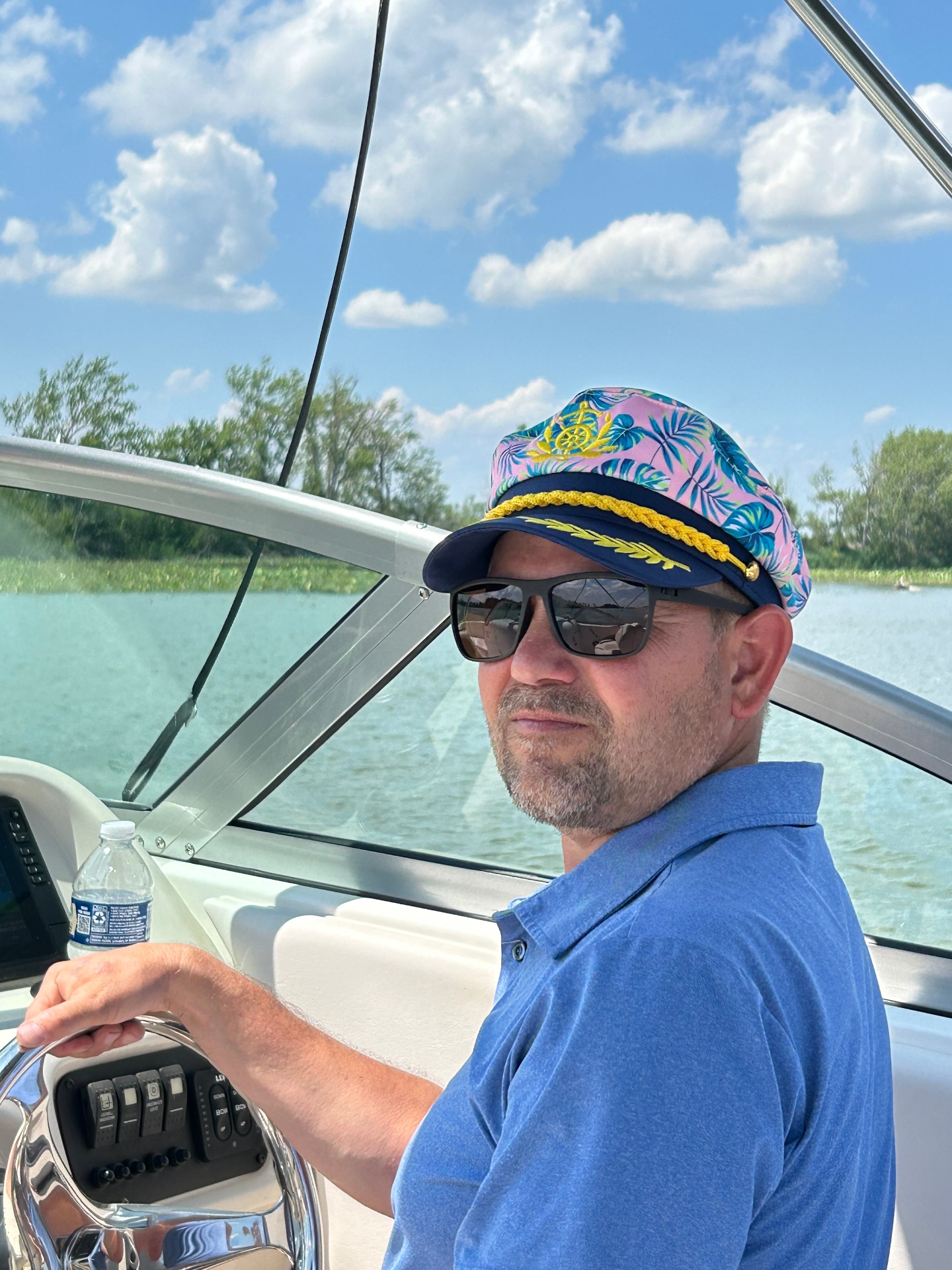 Captain Rob at the helm with hand on wheel, open water and sky in the background